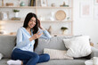 © Prostock-studio - Domestic Rest. Cheerful Asian Woman Relaxing On Couch With Smartphone, Browsing Internet