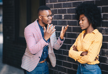 Wall Mural - A young beautiful curly woman stands with her arms crossed together with her man, they look like they are arguing