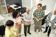 © Svitlana - Group of diverse employees applauding while standing together in the office, Aged woman and man, senior interns having first day at work