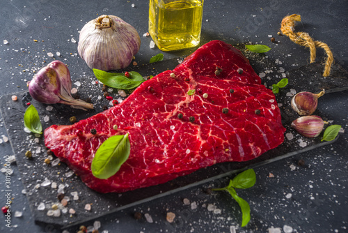 Cuadros en Lienzo Raw meat beef steak on black background, with herbs and spices, top view