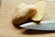 herzförmige Kartoffel aufgeschnitten mit Spitze eines Messers auf Brett 