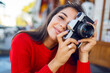 © Svetlana Sokolova - Inspired brunette woman having fun and  making photos on her vacations . Cold season. Wearing stylish red knitted sweater. City background.