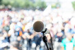 © wellphoto - Focus on microphone, blurred group of people at mass protest in the background