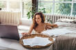 © undrey - Remote work. The woman works at home, sits on the floor in the bedroom and uses a laptop