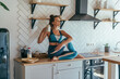 © undrey - Athletic woman having breakfast in the kitchen, girl sitting on table and drinking
