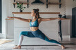 © undrey - Young fit woman exercising at home practicing yoga.