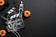 Halloween scary movie concept. Flat lay composition with clapper board, skeleton, spider web, pumpkins on black desk. Halloween background.