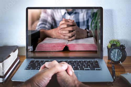 Fotografía Hands praying on bible with computer laptop, Online live church for sunday servi