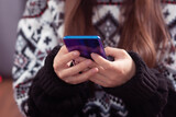 Fototapeta  - Christmas discounts. Girl chooses gifts on a mobile phone