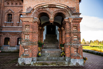 Wall Mural - an old red brick church on a hillock near the forest against a blue sky