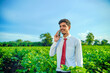 © PRASANNAPIX - young indian handsome agronomist talking on smartphone at field