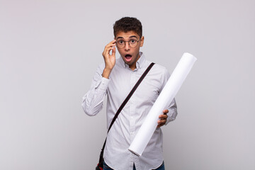 Wall Mural - young architect man looking surprised, open-mouthed, shocked, realizing a new thought, idea or concept