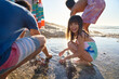 © Trevor Adeline/Caia Image - Portrait happy girl playing in tide pool with family on sunny beach