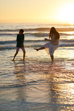 Happy Mother And Son Splashing In Ocean Surf At Sunset