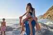 © Trevor Adeline/Caia Image - Happy father carrying daughter on shoulders on sunny ocean beach