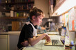 © Paul Bradbury/Caia Image - Boy doing homework at laptop on kitchen counter