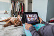 © Paul Bradbury/Caia Image - Woman with digital tablet video chatting with friends on bed with dog