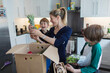 © Paul Bradbury/Caia Image - Happy mother and sons unloading fresh produce from box in kitchen