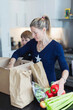 © Paul Bradbury/Caia Image - Mother and son unloading fresh produce in kitchen