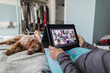 © Paul Bradbury/Caia Image - Woman with digital tablet video chatting with friends on bed with dog