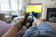 © Paul Bradbury/Caia Image - POV man with remote control watching soccer match on living room sofa