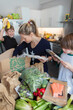 © Paul Bradbury/Caia Image - Woman and sons unloading fresh produce from box in kitchen
