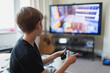 © Paul Bradbury/Caia Image - Boy playing video game at TV in living room