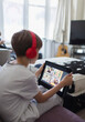 © Paul Bradbury/Caia Image - Boy with headphones and digital tablet homeschooling on sofa
