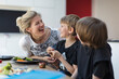 © Paul Bradbury/Caia Image - Happy mother and sons eating dinner at table
