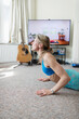 © Paul Bradbury/Caia Image - Woman practicing yoga at TV in living room