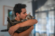 © magui RF - hombre joven sostiene a un gato entre sus brazos y lo besa