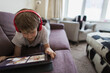 © Paul Bradbury/Caia Image - Boy with headphones and digital tablet homeschooling on sofa