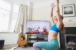 © Paul Bradbury/Caia Image - Woman practicing yoga at TV in living room