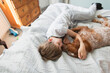 © Paul Bradbury/Caia Image - Affectionate boy cuddling dog on bed