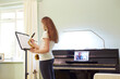 © Adam Gault/Caia Image - Girl taking online saxophone lesson at home