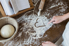 Teenage Girl Drawing Heart Shape In Flour On Kitchen Counter