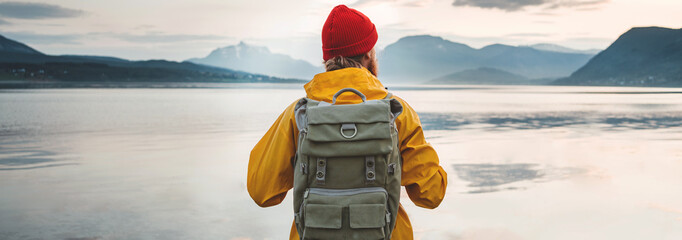 Wide image. Man traveler wearing yellow jacket with backpack explore scandinavia nature. Wanderlust outdoor