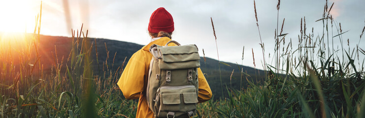 Wall Mural - Back view of man tourist with backpack standing in front of the mountain massif while journey by scandinavian. Wide image