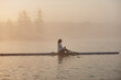 © Dann - Side view of woman rowing single scull in lake at early morning