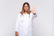 young woman physician looking serious, stern, displeased and angry showing open palm making stop gesture