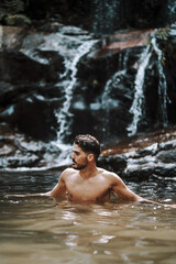 Sticker - Young Caucasian male having a fun time at a beautiful waterfall near rocks