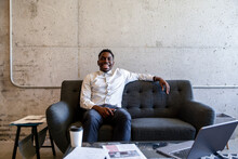 Portrait Of Designer Smiling On Sofa In Office Breakout Area
