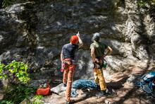 Young Male Rock Climbers Looking Up At Rock Face