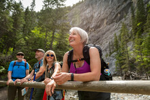 Smiling Mature Woman Hiking With Friends In Sunny Woods