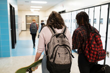 Students With Backpacks Walking Down School Corridor