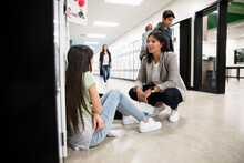 Teacher Talking To Student In School Corridor