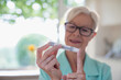 © Tom Merton/Caia Image - Senior woman with diabetes using blood glucose meter on finger