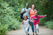 © Paul Bradbury/Caia Image - Happy family running and hiking on trail in woods