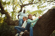 © Paul Bradbury/Caia Image - Father and daughters climbing tree