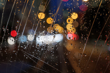 Wall Mural - Selective focus at scratch and rain drops on glass of back of vehicle with blur night view with golden bokeh of street.
